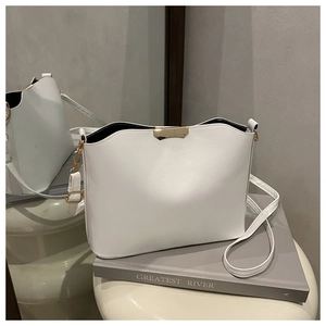 Detail view of white glossy handbag with wavy top design and rectangular gold metal buckle