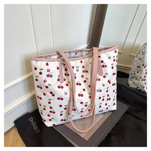 Détail d'un grand sac cabas blanc imprimé cerises avec des anses en cuir rose