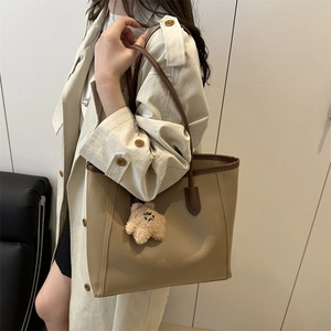 Minimalist beige tote bag with dark brown contrast edges and plush bear charm decoration