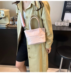 Détail du sac cabas plissé rose avec bandoulière large porté avec un trench vert