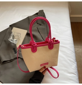 Détail d'un sac seau en paille beige avec bordure en similicuir magenta et poignée nouée