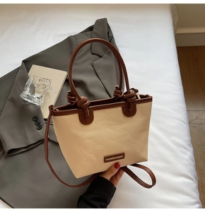Détail de la texture paille beige et de la bandoulière en cuir marron du sac seau