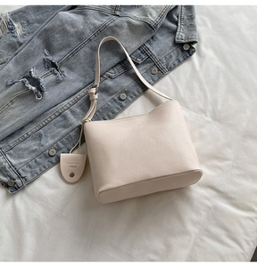 Detail of a creamy beige bucket bag with lychee texture next to a denim jacket