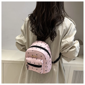 Close-up of pink mini backpack with bunny prints on model wearing a beige coat