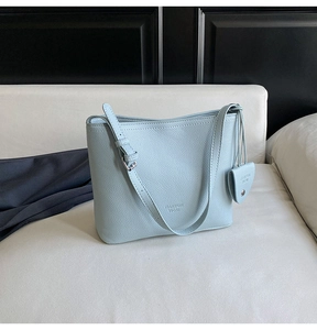 Detail of light blue bucket bag with lychee texture and matching small pendant charm