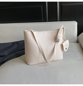 Detail of cream lychee-patterned bucket bag with adjustable strap and coin purse charm