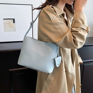 Minimalist light blue lychee pattern shoulder bucket bag with mini charm on beige coat