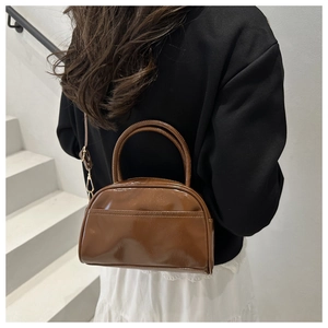 Détail du sac bandoulière marron en cuir verni brillant avec sangle et poignée