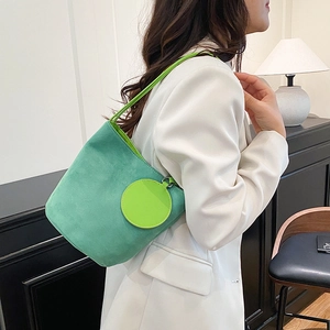 Sac seau vert en daim mat avec pochette assortie, porté par un mannequin en intérieur