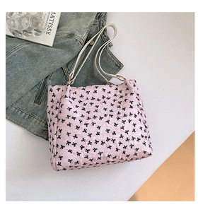 Close-up of pink tote bag with black bow patterns and textured fabric on a white surface