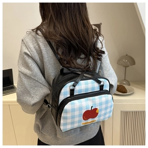 Blue gingham pattern backpack detail with red apple print and black PU leather strap