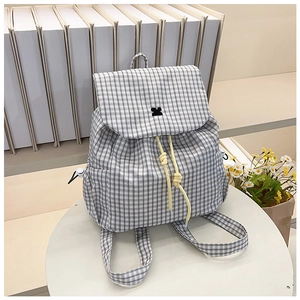 Detail view of plaid backpack featuring cartoon embroidery and bright yellow drawstring cord