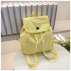 Detail view of the yellow drawstring backpack showing the unique wrinkled fabric and logo