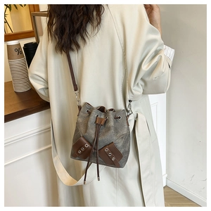 Détail d'un sac seau en toile grise avec garniture en cuir brun et œillets métalliques