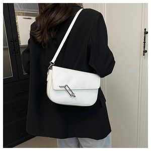 Detail showing white faux leather saddle bag with distinctive silver paperclip clasp