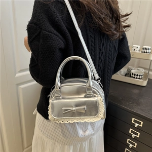 Borsa metallizzata argento con fiocco e pizzo indossata sulla schiena del modello