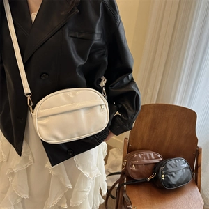 Minimalist solid color oval crossbody bag with adjustable strap in black, brown and white