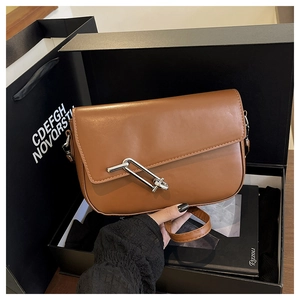 Close-up of brown matte leather saddle bag featuring a unique silver metal latch buckle