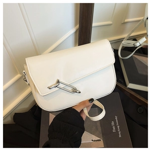 Detail of white saddle bag featuring a large silver metal buckle and matte leather texture
