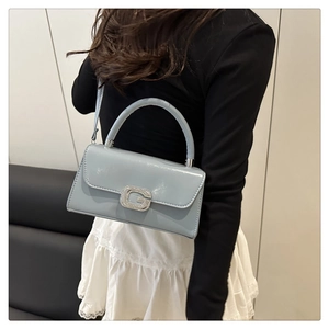 Détail du sac à main en cuir verni bleu clair avec boucle G en strass et poignée