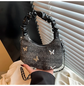 Close-up of hobo bag with silver metallic butterflies and pleated black handle detail