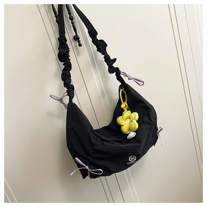 Détail du sac croissant noir avec nœuds violets et breloque peluche tournesol jaune
