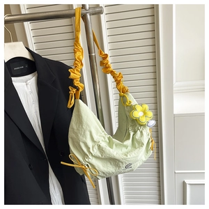 Détail du sac croissant vert clair avec bandoulière froncée jaune et pendentif fleur