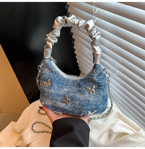 Detail of blue denim bag with silver butterfly accents and glossy metallic handle