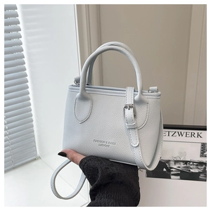 Detail showing textured light blue leather handbag with metal buckle and logo print