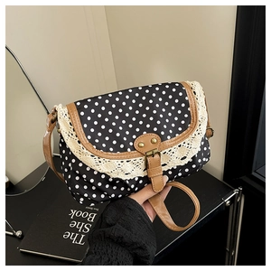 Dettaglio borsa vintage in tela a pois con pizzo e cinturini in pelle marrone