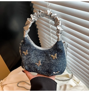 Detail of denim crescent bag with silver butterfly metal charms and rhinestones