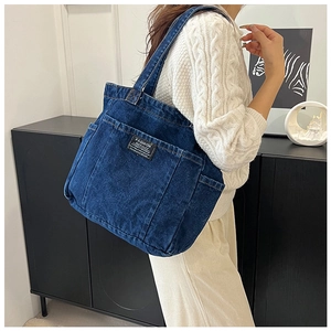 Detail view of washed denim tote bag with functional pockets and Fashion Instinct label