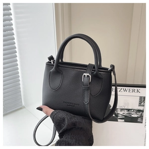 Detail of black lychee grain leather tote bag with silver buckle and crossbody strap