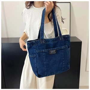 Detail of blue denim tote bag with multiple pockets and Fashion Instinct patch