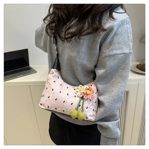 Détail du sac demi-lune plissé rose avec imprimé lettres et breloque fleur tressée