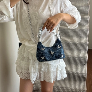 Navy denim crescent handbag with silver butterfly accents and chain strap in luxury style