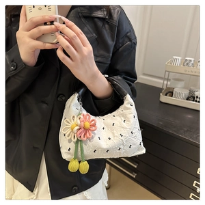 Détail du sac à main blanc gaufré avec imprimé lettres, poignée cuir et pendentif fleuri