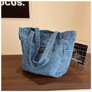 Detail of blue washed denim tote bag showing multiple utility pockets and woven label