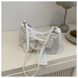 Détail du sac à main blanc en texture jacquard avec un grand nœud et des perles chic