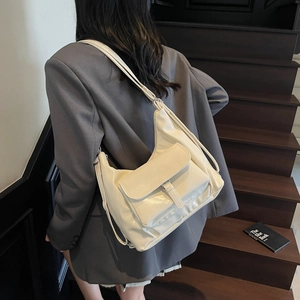 Sac à bandoulière chic en similicuir brillant blanc crème porté avec un blazer gris