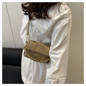Detailed view of khaki woven shoulder bag with wavy edge flap and gold metal buckle