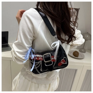 Close-up of black Y2K shoulder bag featuring metal chains, star charms and red heart patches