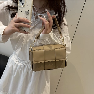 Petit sac carré à bandoulière en cuir tressé kaki avec chaîne dorée présenté par un mannequin
