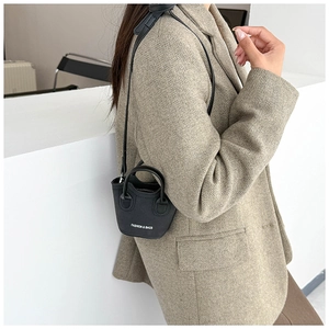 Dettaglio mini borsa a secchiello in pelle nera trendy con scritta bianca e tracolla sottile