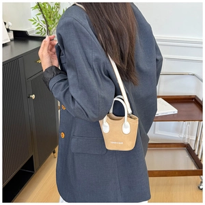Mini borsa a secchiello in pelle kaki indossata con un blazer grigio per un look moderno