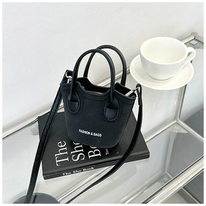 Dettaglio macro della mini borsa nera con scritte bianche su sfondo di scena elegante