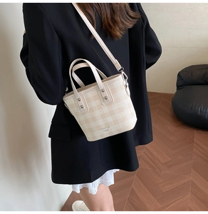 Vue arrière d'une femme portant un sac seau chic à carreaux beige avec bandoulière