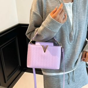 Purple woven leather handbag with gold V logo and detachable strap in a fashion scene