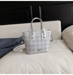 Détail du sac à main en cuir à carreaux argentés avec logo métallique et finitions argentées