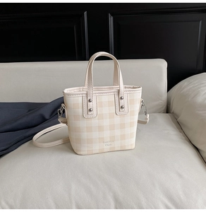 Détail d'un sac seau à carreaux beige avec doubles poignées et détails en métal argenté poli